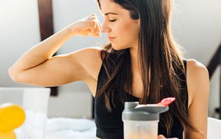 woman flexing arm muscle with orange juice in hand
