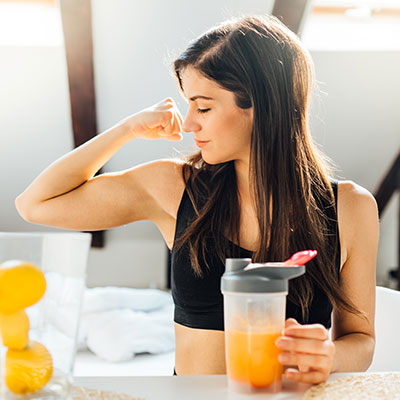 woman flexing arm muscle with orange juice in hand